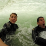 August 2014  Die GoPro ist mittlerweilen immer häufiger im Einsatz und natürlich ganz besonders bei Aktion im Wasser. Diesmal wollten wir ein Foto schießen, bei dem wir in der über uns brechenden Welle eingeschlossen sind. Und das ist gar nicht so einfach. Trotz einer Bildfrequenz von zehn Bildern pro Sekunde trifft man nicht immer den richtigen Augenblick und nicht immer bildet sich beim brechen der Welle ein geeigneter Tunnel. Einmal hatten wir Glück. Alles hat gepasst. Während Marvin beim Auslösen noch gelassen in die Kamera blickt, ist mir schon die Aufregung ins Gesicht geschrieben ...